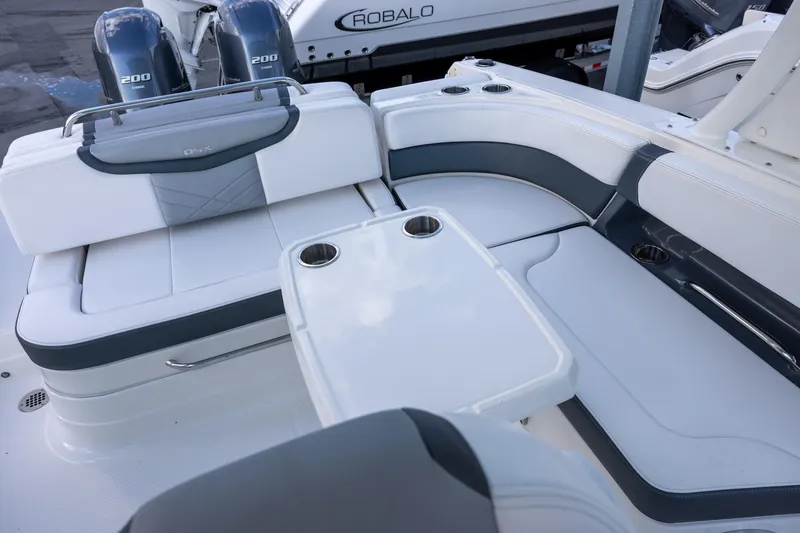 Slide: The Image of 2021 Chaparral 280 OSX boat interior with seating and table, featuring dual outboard engines. - 9
