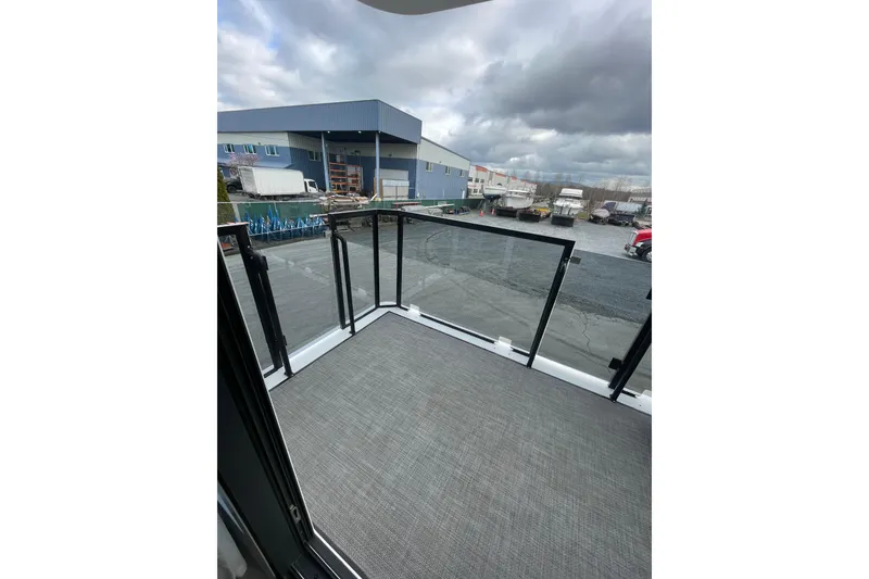 Slide: The Image of Modern houseboat balcony with glass railing, overlooking industrial area under cloudy sky. Houseboat model: ALLHOUSE HB-1250, 2025. - 20