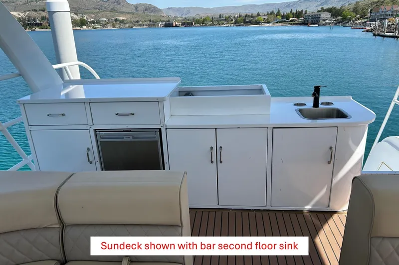 Slide: The Image of Houseboat sundeck with bar and sink, overlooking serene blue waters, 2025 model. - 27
