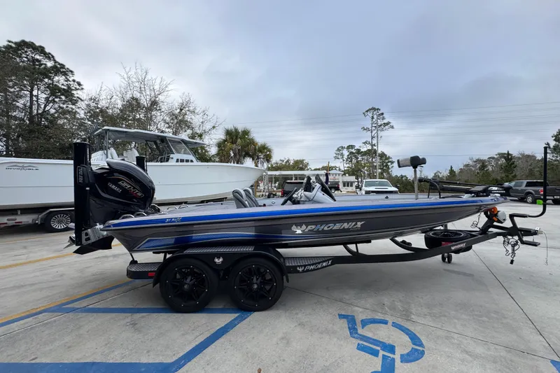 Slide: The Image of 2023 Phoenix 21 PHX boat on trailer, parked in a lot with trees and vehicles. - 10