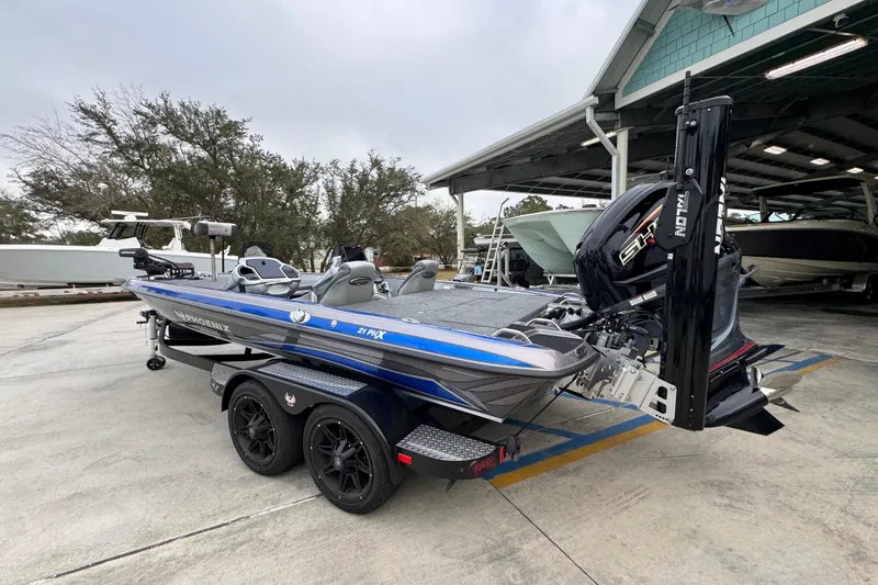 Slide: The Image of 2023 Phoenix 21 PHX boat with dual axle trailer, parked outdoors near other boats. - 16