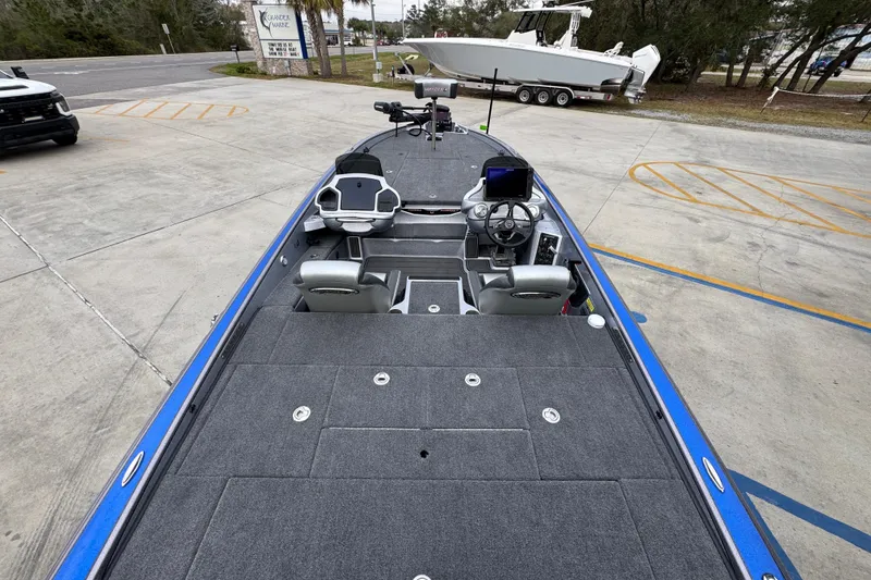 Slide: The Image of 2023 Phoenix 21 PHX boat with spacious deck and modern controls, parked outdoors. - 36