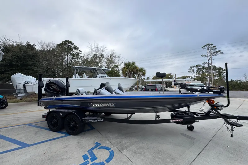 Slide: The Image of 2023 Phoenix 21 PHX boat on trailer, parked outdoors with trees in background. - 9