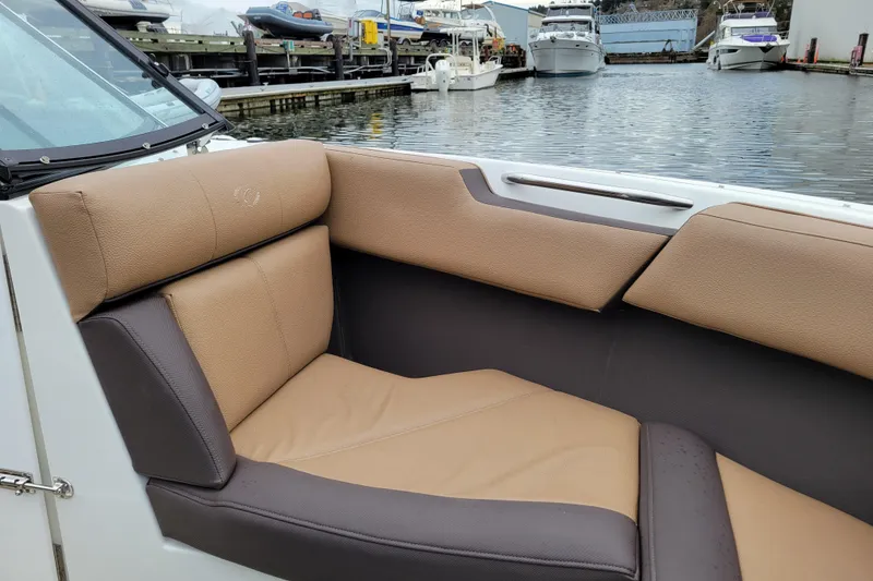 Slide: The Image of 2019 Cobalt CS22 boat interior with tan and brown seating at a marina. - 14