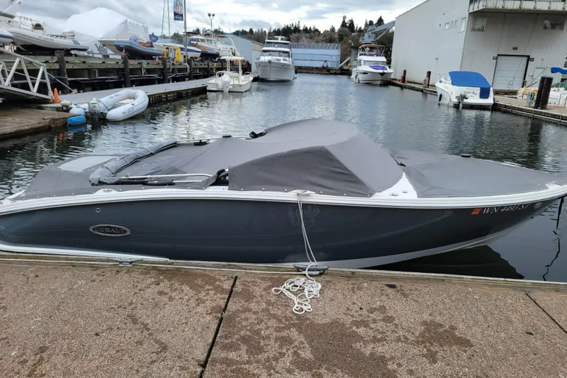 Slide: The Image of 2019 Cobalt CS22 boat docked with cover, in a marina setting. - 28