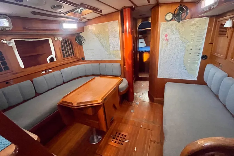 Slide: The Image of Cozy 1982 Stevens cutter yacht interior with wooden furnishings and nautical maps. - 13