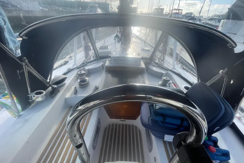 Slide: The Image of 1982 Stevens cutter sailboat cockpit with steering wheel, winches, and seating, docked at marina. - 7