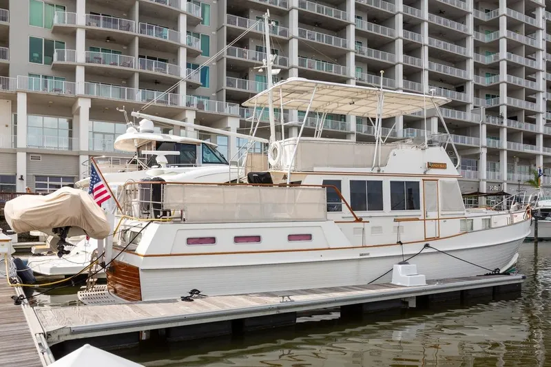 The Image of 1993 Grand Banks 46 Motoryacht docked at marina, with modern building backdrop. - 0