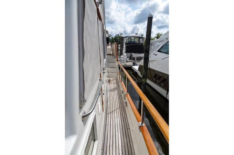 Slide: The Image of 1993 Grand Banks 46 Motoryacht docked, showcasing wooden deck and marina view. - 17