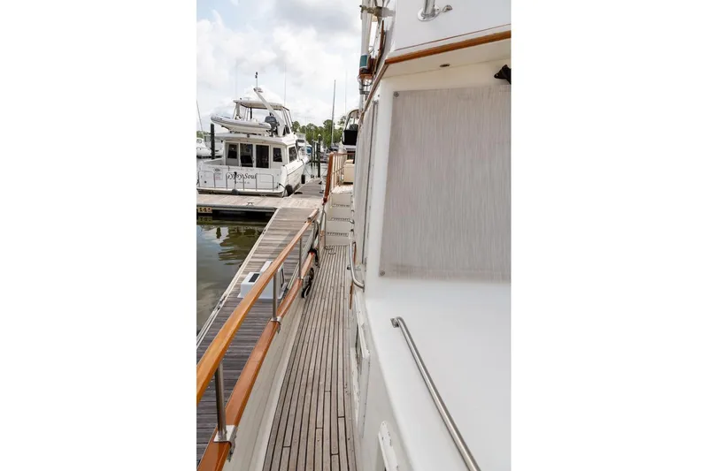 Slide: The Image of 1993 Grand Banks 46 Motoryacht with spacious deck and canopy, docked under a sunny sky. - 18