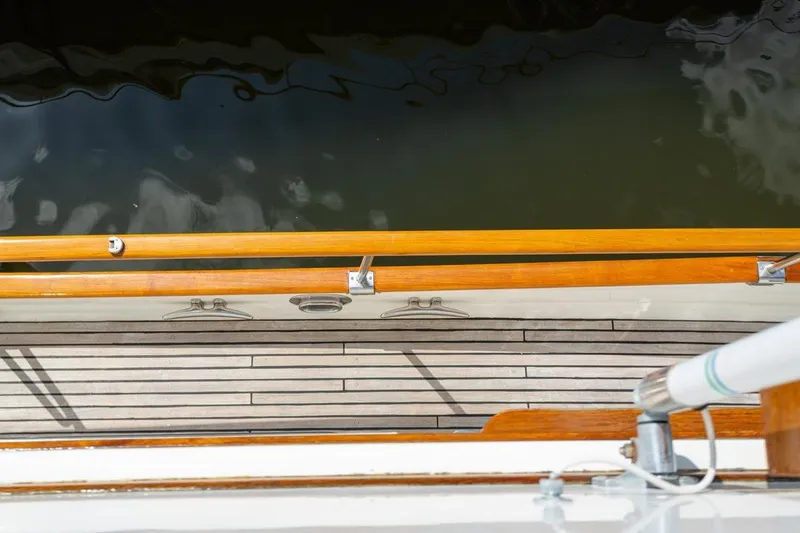 Slide: The Image of Wooden deck and railing of 1993 Grand Banks 46 Motoryacht, with metal cleats. - 38