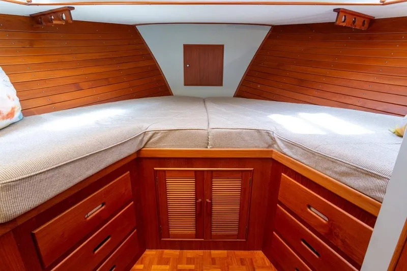 Slide: The Image of 1993 Grand Banks 46 Motoryacht cabin with cozy bed, wooden accents, and colorful pillows. - 44
