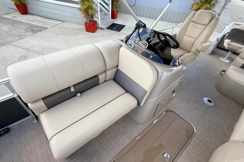 Slide: The Image of 2022 Sun Tracker Fishin' Barge 22 DLX interior with beige seating and steering console. - 15