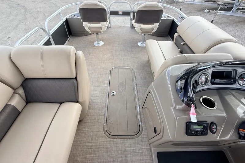 Slide: The Image of 2022 Sun Tracker Fishin' Barge 22 DLX interior with beige seating and control panel. - 21