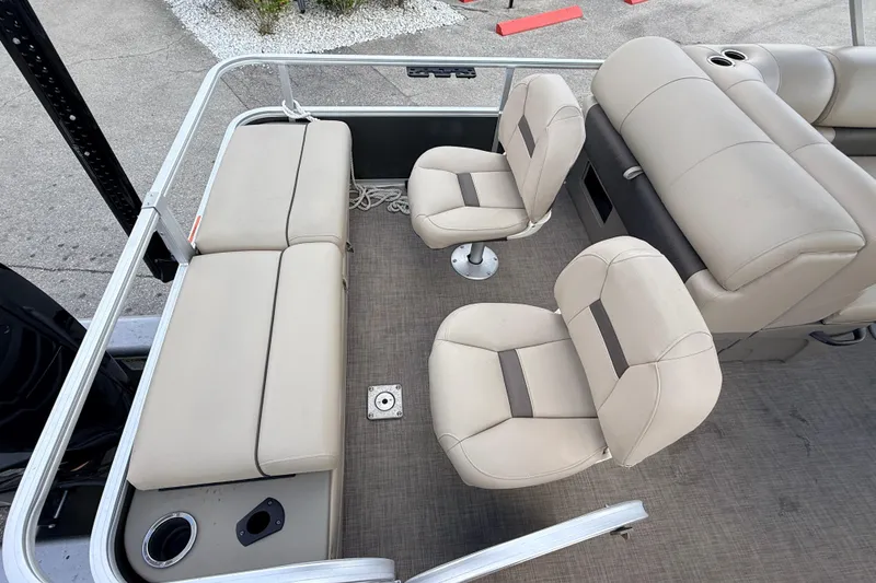 Slide: The Image of 2022 Sun Tracker Fishin' Barge 22 DLX interior with beige seating and cup holders. - 23