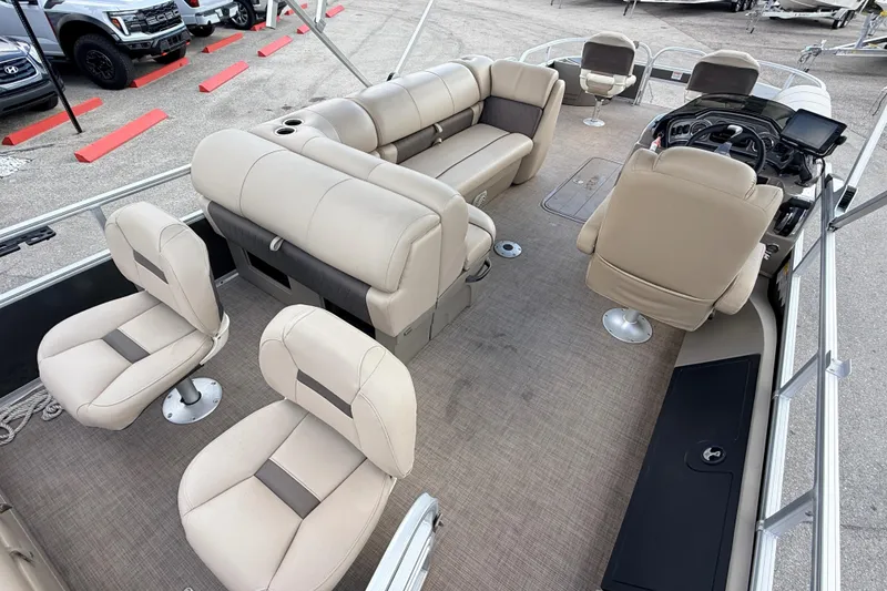 Slide: The Image of 2022 Sun Tracker Fishin' Barge 22 DLX interior with beige seating and steering console. - 24