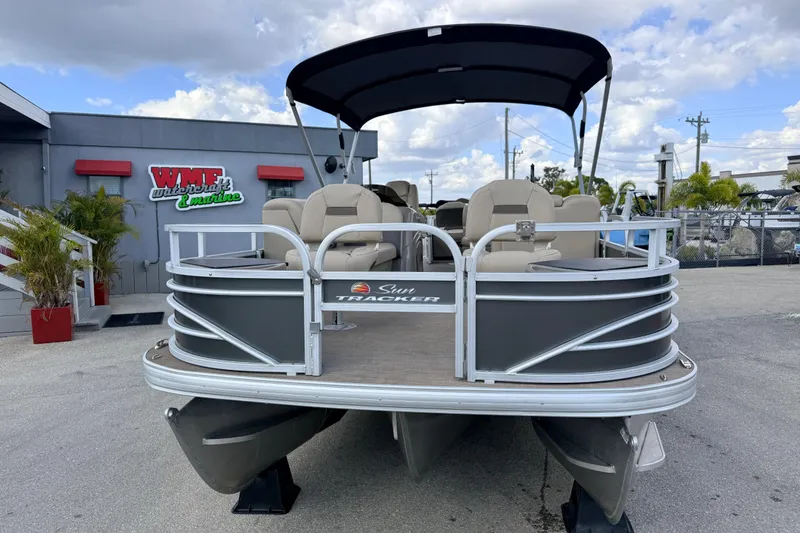 Slide: The Image of 2022 Sun Tracker Fishin' Barge 22 DLX pontoon boat at dealership, under cloudy sky. - 4
