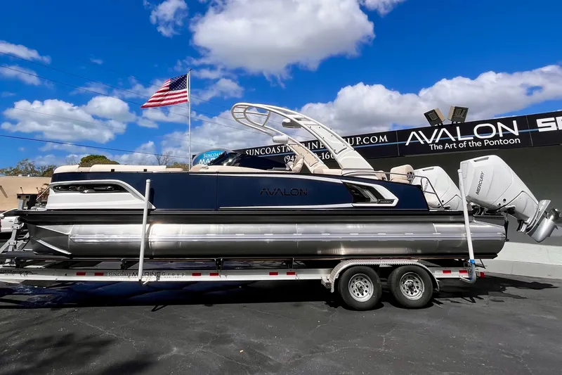 The Image of 2026 Avalon Excalibur pontoon boat on trailer, blue sky. - 1
