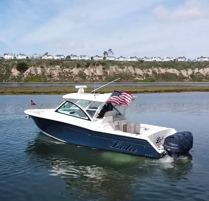 Slide: The Image of 2017 Grady-White Freedom 375 boat on water, American flag, coastal background. - 2