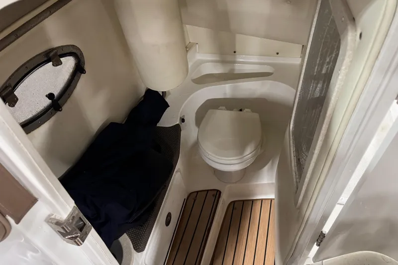 Slide: The Image of 2007 Cobalt 282 boat interior with compact bathroom, featuring a toilet and wooden flooring. - 13