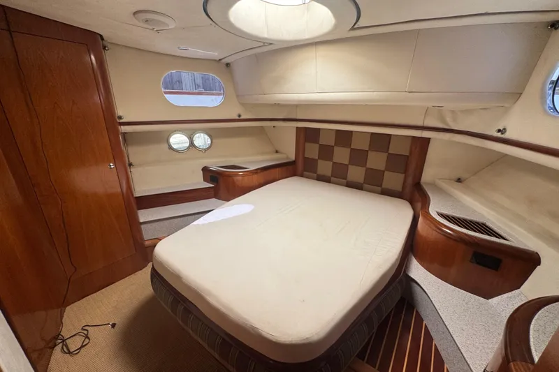Slide: The Image of 2003 Custom Sea Star Pilot House cabin interior with bed, wood paneling, and portholes. - 18