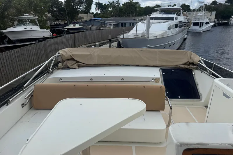 Slide: The Image of 2003 Custom Sea Star Pilot House boat docked, featuring a covered seating area and nearby yachts. - 25