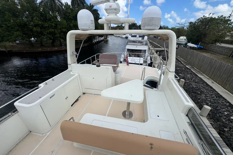 Slide: The Image of 2003 Custom Sea Star Pilot House boat deck with seating and table, docked by a canal. - 26
