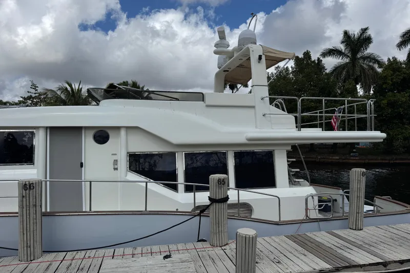 Slide: The Image of Custom 2003 Sea Star Pilot House yacht docked, with palm trees and cloudy sky in the background. - 3