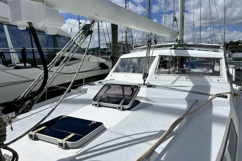 Slide: The Image of 1986 Amel Mango sailboat deck with rigging, docked at marina under cloudy sky. - 10