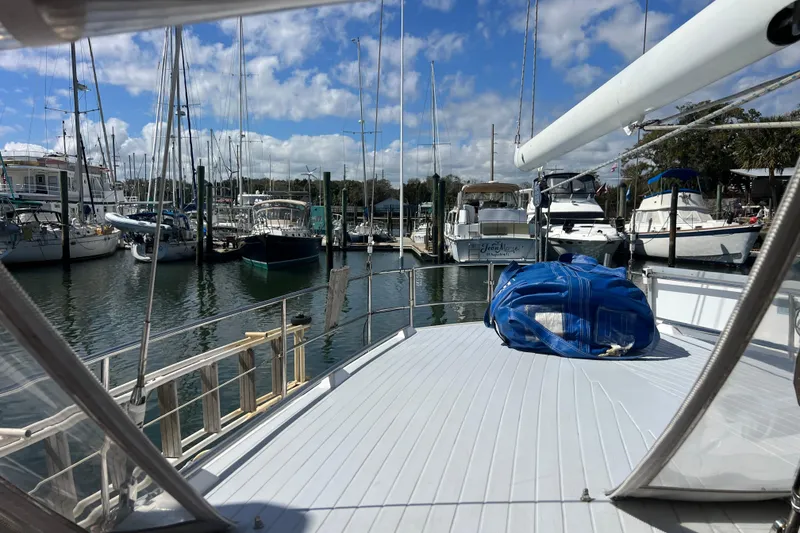 Slide: The Image of 1986 Amel Mango sailboat docked in a marina under a blue sky. - 16