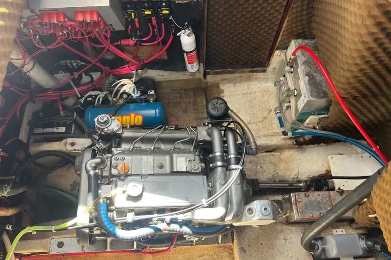 Slide: The Image of Engine room of a 1986 Amel Mango sailboat with visible wiring and components. - 25