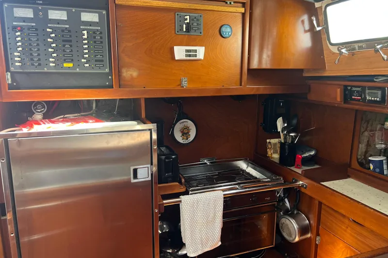 Slide: The Image of 1986 Amel Mango yacht kitchen with wooden cabinets, stainless steel appliances, and control panels. - 38