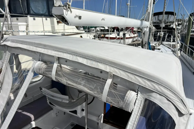 Slide: The Image of 1986 Amel Mango sailboat with white canopy and marina background. - 56