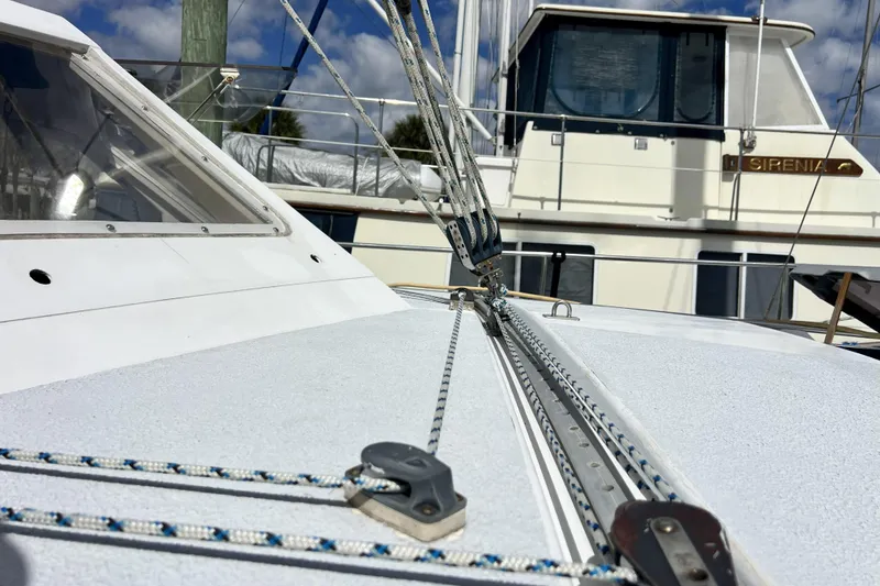 Slide: The Image of Sailboat deck of 1986 Amel Mango with rigging details, docked near another vessel. - 59