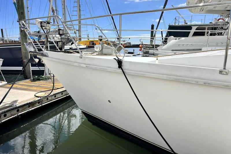 Slide: The Image of 1986 Amel Mango sailboat docked at marina, featuring sleek white hull and stainless steel railings. - 9