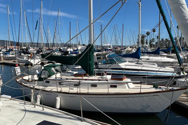 The Image of 1985 Mason 33 sailboat docked in a marina, surrounded by other boats. - 0
