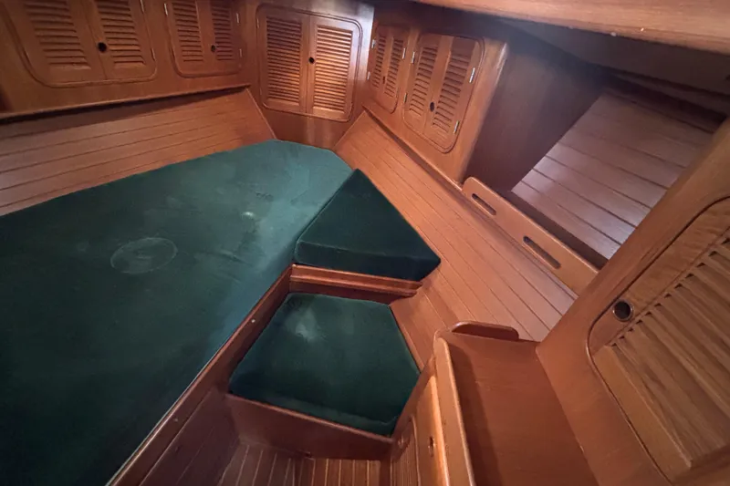 Slide: The Image of Cozy cabin interior of 1985 Mason 33 sailboat with green cushions and wooden paneling. - 22