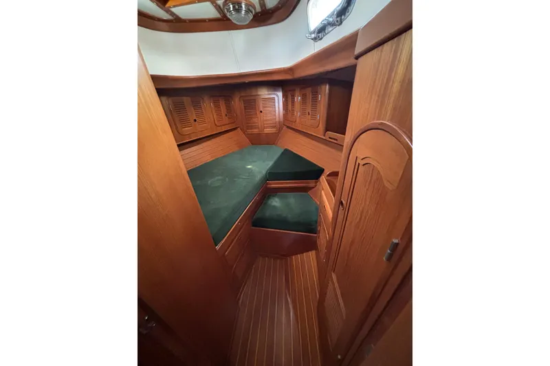Slide: The Image of Interior of a 1985 Mason 33 sailboat with wooden paneling and green cushions. - 23