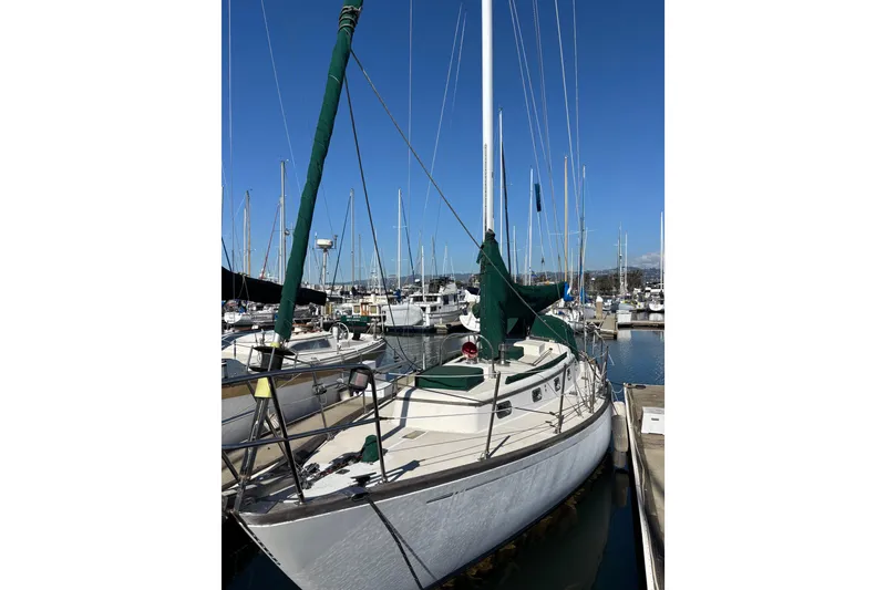 Slide: The Image of 1985 Mason 33 sailboat docked at marina, featuring green sail covers. - 3