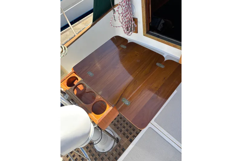 Slide: The Image of Wooden cockpit table on 1985 Mason 33 sailboat, featuring cup holders and rope storage. - 30