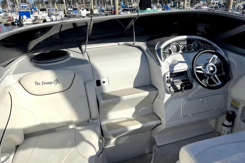Slide: The Image of 2004 Crownline 250 CR boat interior with steering wheel and seating at marina. - 16