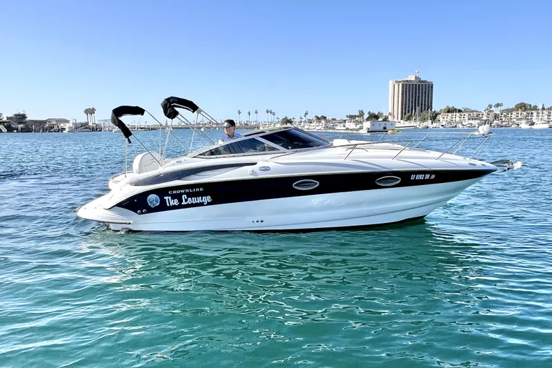 Slide: The Image of 2004 Crownline 250 CR boat on calm water with cityscape background. - 2