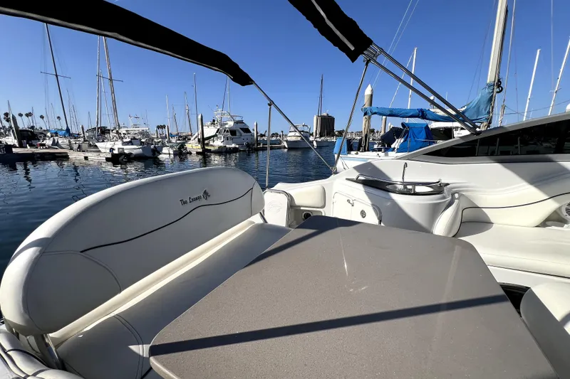 Slide: The Image of 2004 Crownline 250 CR boat interior with marina view, featuring seating and table. - 24