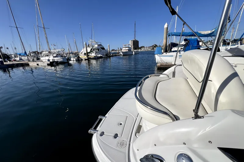 Slide: The Image of 2004 Crownline 250 CR boat docked in a marina with sailboats and clear blue sky. - 26