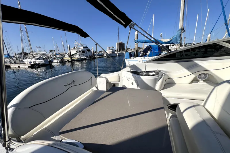 Slide: The Image of 2004 Crownline 250 CR boat interior at marina, featuring white seating and table. - 27