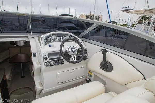 Slide: The Image of 2004 Crownline 250 CR boat interior with steering wheel and dashboard, docked at marina. - 32