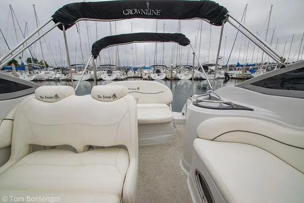 Slide: The Image of 2004 Crownline 250 CR boat interior with white seating, docked at a marina. - 34