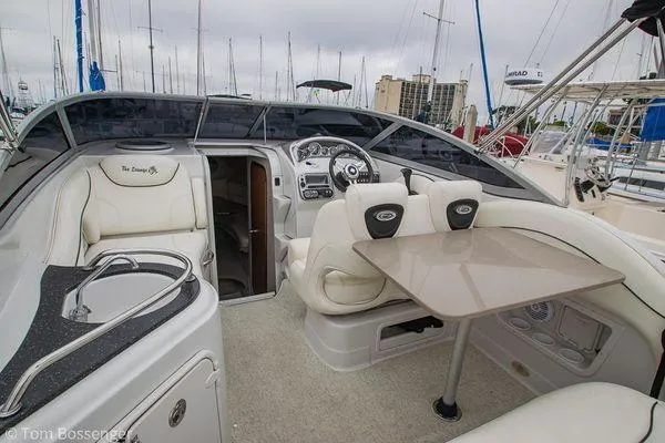 Slide: The Image of 2004 Crownline 250 CR boat interior with seating, table, and helm in a marina setting. - 36