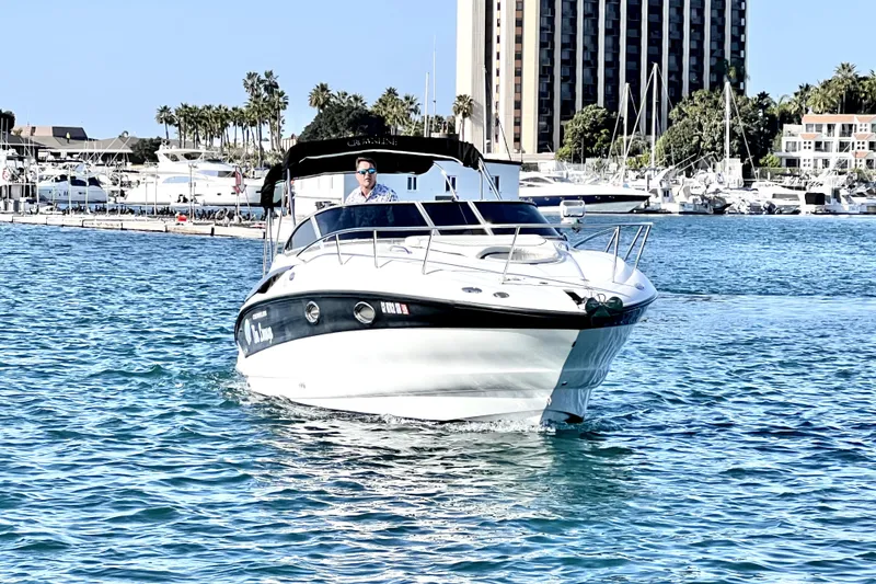 Slide: The Image of 2004 Crownline 250 CR boat cruising in a sunny marina with palm trees and buildings. - 4