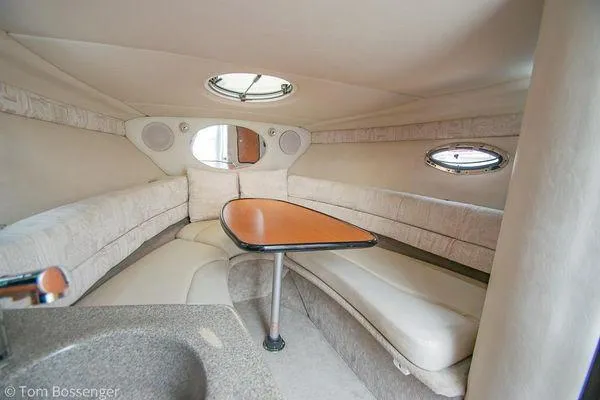 Slide: The Image of 2004 Crownline 250 CR cabin interior with seating and table, featuring portholes and a skylight. - 40